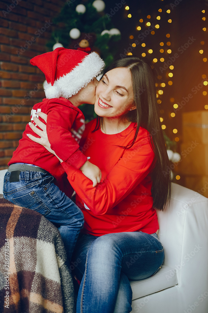 Cute family have fun in decorating room. Beautiful mother with little son. Family in a red sweaters Cute family have fun in decorating room. Beautiful mother with little son. Family in a red sweaters