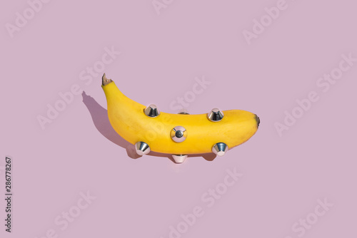 banana dressed with tacks isolated on pink background
