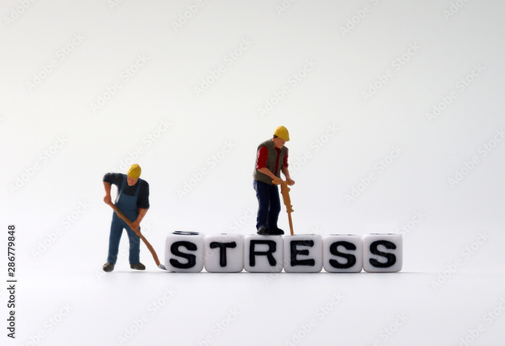 The word STRESS on white cubes with miniature people. The word STRESS on white cubes with miniature people.