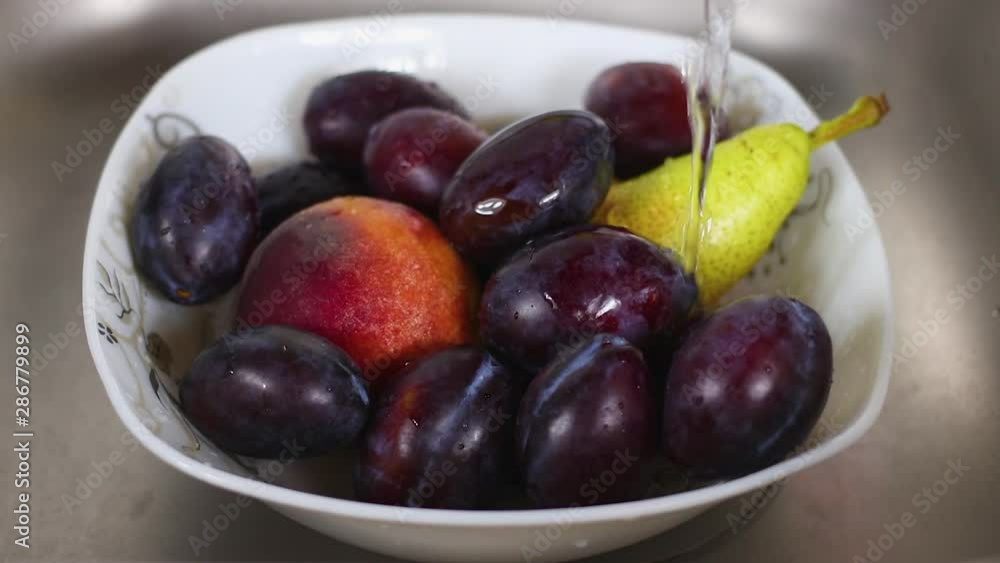 Pouring fresh and clean water on organic fruit in white dish. Fresh water drops in white dish full of organic fruits Pouring fresh and clean water on organic fruit in white dish. Fresh water drops in white dish full of organic fruits