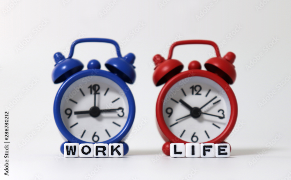 The WORK word and LIFE word on white cubes in front of the two alarm clock. 