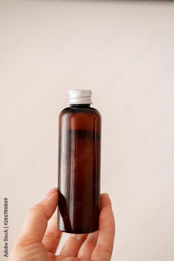 Woman holding glass cosmetic  brown bottle