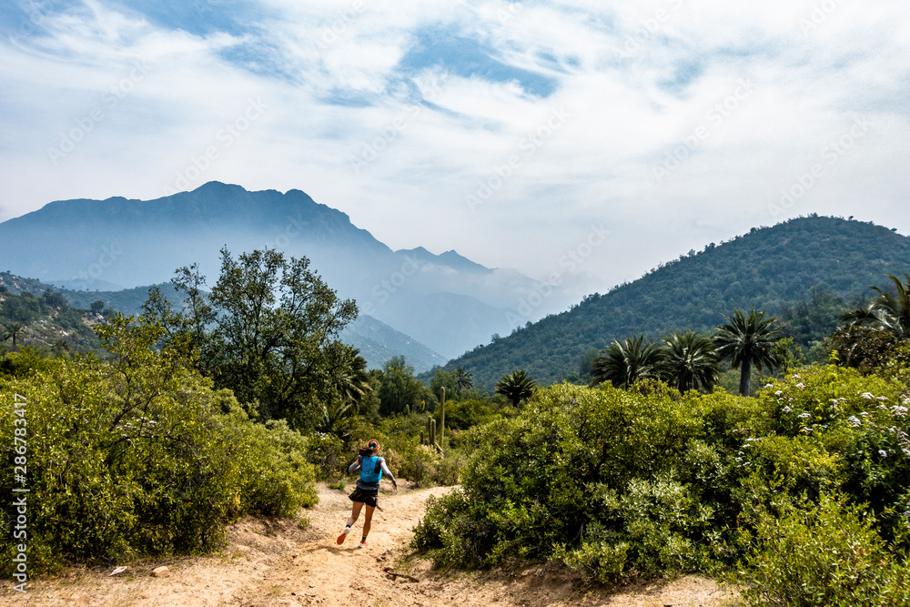 Young woman trail running through National Park La Campana in Chile.  