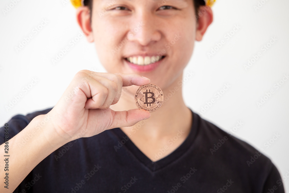Young asian man hold golden bitcoin coins in hand. Virtual currency. Crypto currency. New virtual money. Young asian man hold golden bitcoin coins in hand. Virtual currency. Crypto currency. New virtual money.