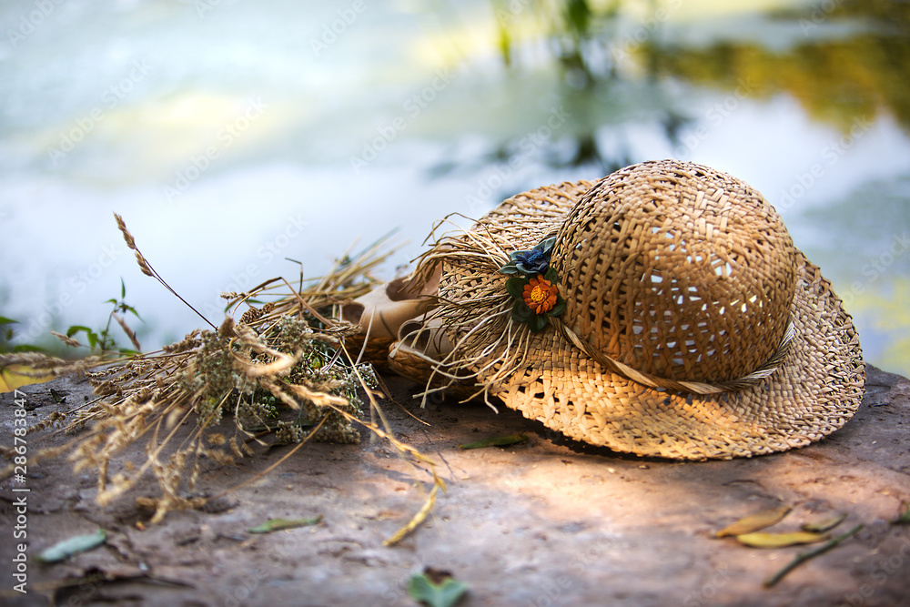 straw hat with a bouquet of flowers on a background surface of the water