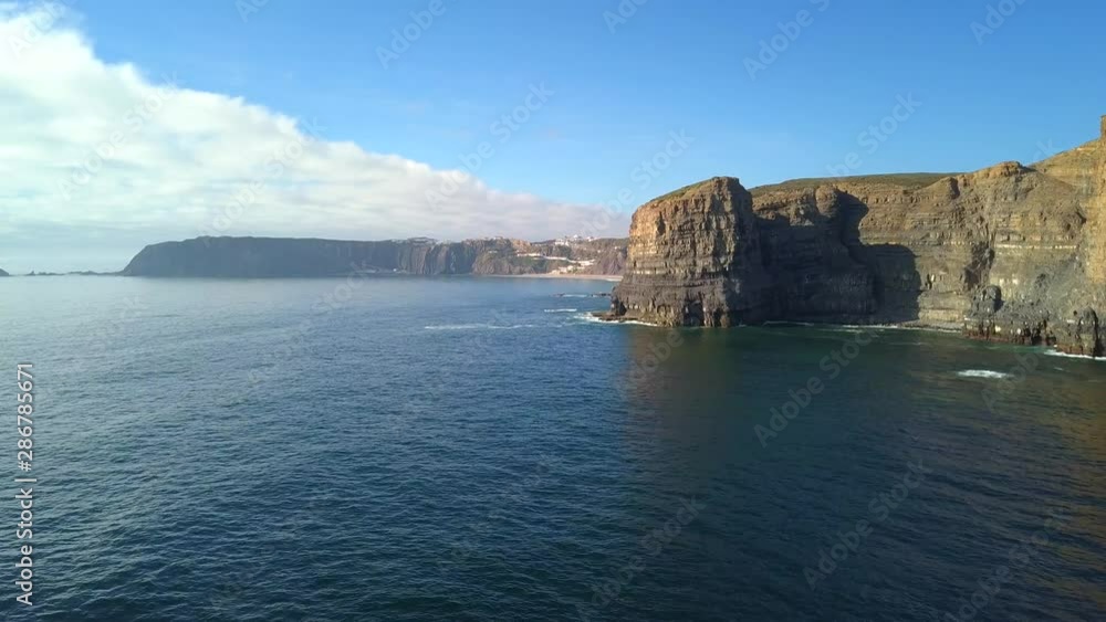 Aerial, rising, drone shot, over cliffs, towards the Arrifana beach, on the Atlantic coast, near the Pedra da Agulha, at Aljezur,, on a sunny day, in Vicentine coast national park, Algarve, Portugal Aerial, rising, drone shot, over cliffs, towards the Arrifana beach, on the Atlantic coast, near the Pedra da Agulha, at Aljezur,, on a sunny day, in Vicentine coast national park, Algarve, Portugal