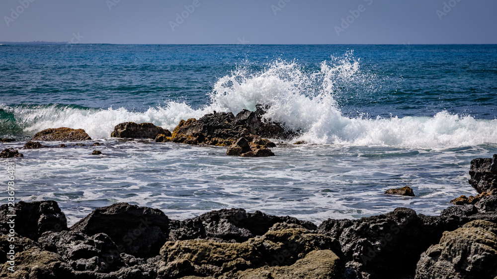 Waves crash on rough volcanic rocks