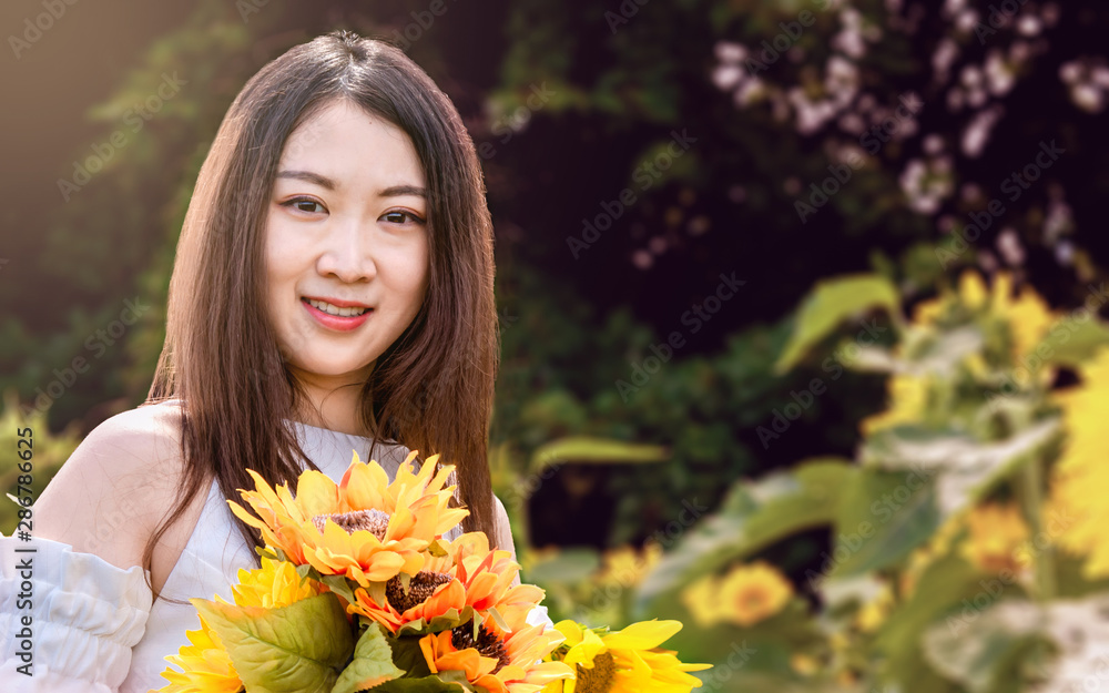 A young oriental girl with long hair and white dress in a field of sunflowers A young oriental girl with long hair and white dress in a field of sunflowers