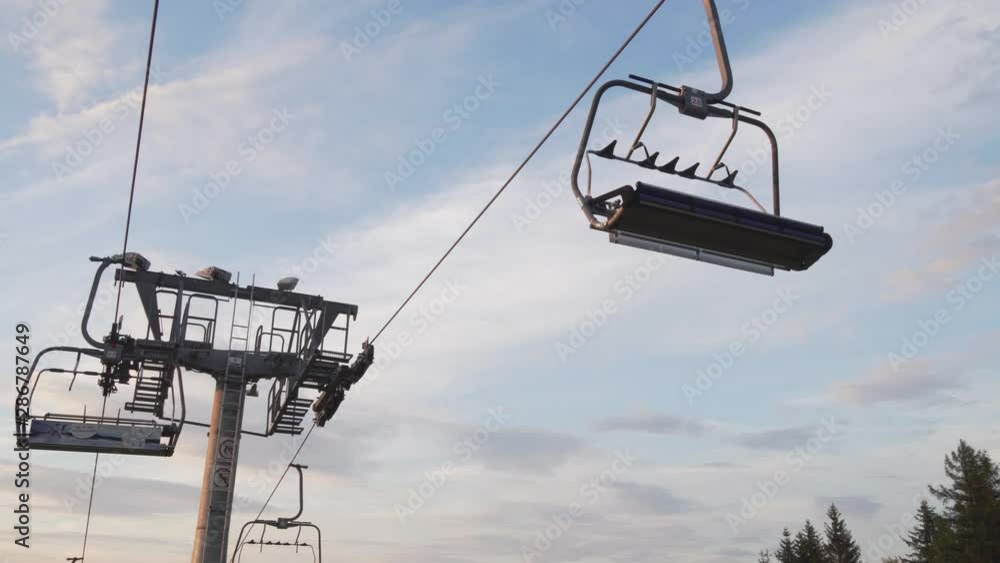 Closed ski lift in the summer, low angle shot with panorama background, man walking down Closed ski lift in the summer, low angle shot with panorama background, man walking down
