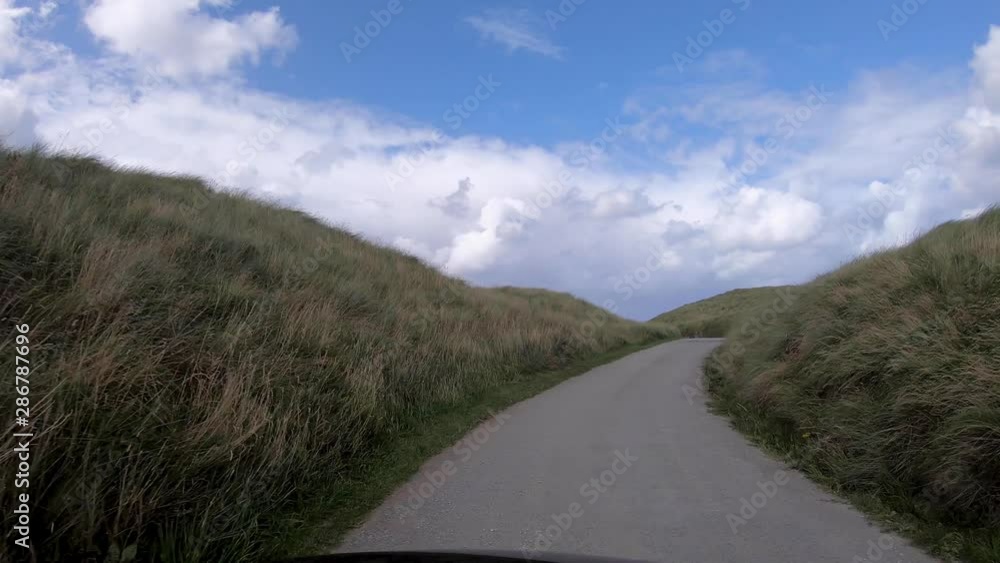 Wide Shot of Driving to the Beach on a Sunny Day through Dunes with Windy Grass Blowing Wide Shot of Driving to the Beach on a Sunny Day through Dunes with Windy Grass Blowing