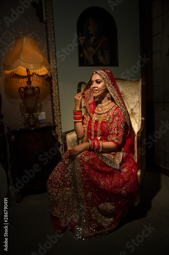 Valokuvatapetti Beautiful traditional Indian girl sitting on sofa like a princess wearing ethnic