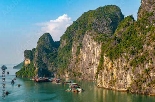 A floating village among the geologic karst rock formations of Halong Bay at sunset, North Vietnam.