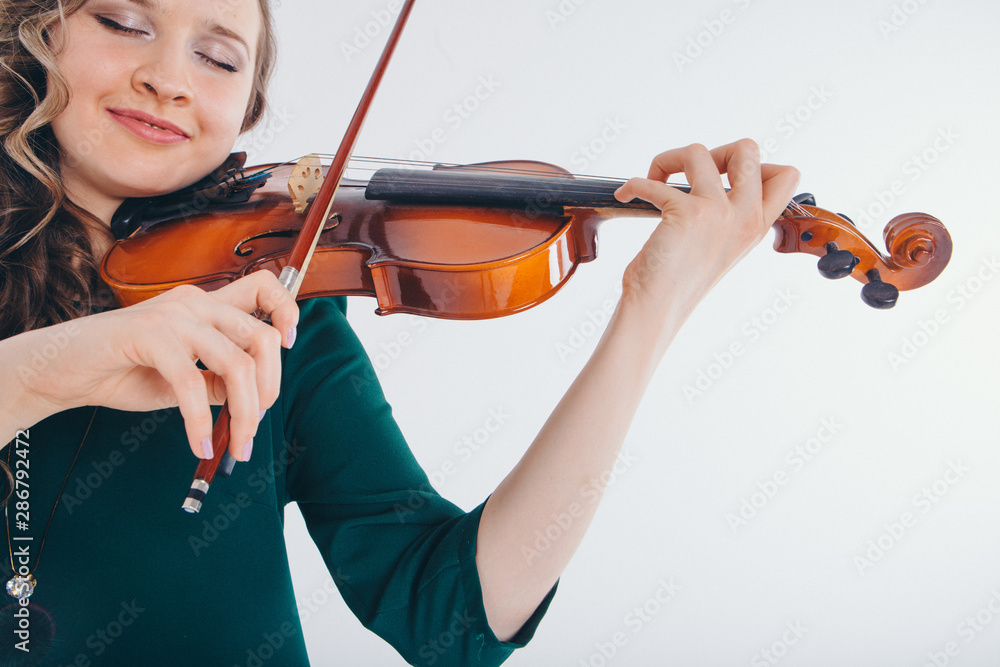 beautiful girl in green dress with small guitar in hands on white background. The concept of advertising musical instruments, fashion, symbols