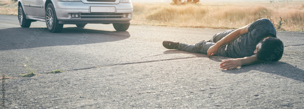 Caucasian injured man lying on asphalt. - obrazy, fototapety, plakaty 