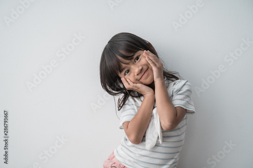 cute smiling little girl with hands on cheek in the isolated background