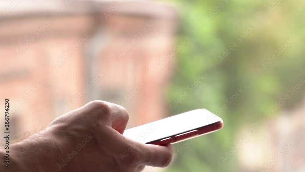 Young caucasian adult holding a smartphone cell in his hands and typing with his fingers a text message Young caucasian adult holding a smartphone cell in his hands and typing with his fingers a text message