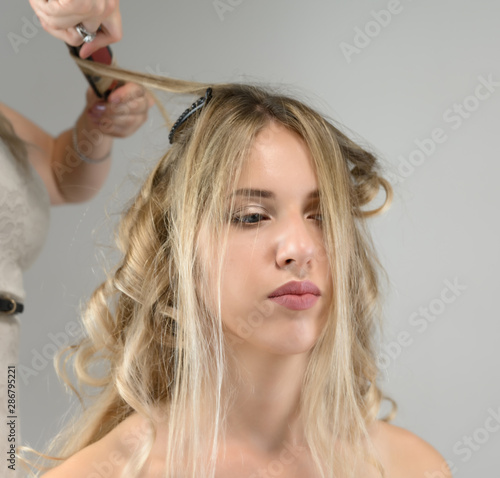 A photo of a hairdresser working on a model s hair in a studio. Makes a hairstyle  styling hair on a white background.