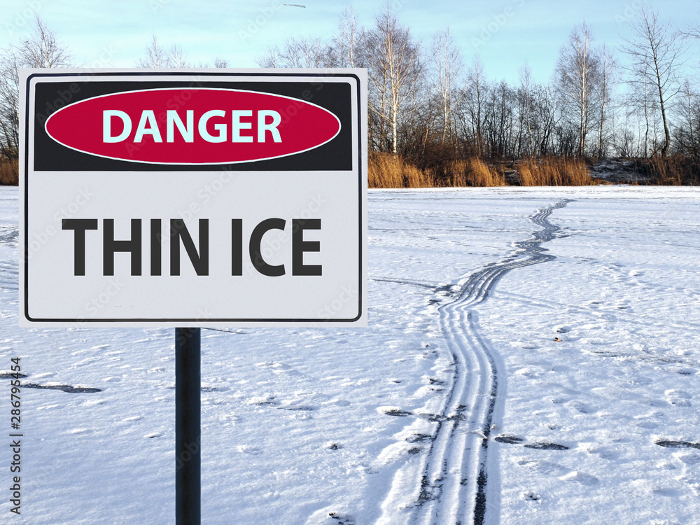 Foto de sign danger thin ice and footprints road on snow and ice do Stock