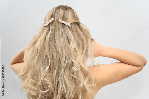 A large photo portrait of a pretty model with long hair and a beautiful hairstyle on a white background. Back view.