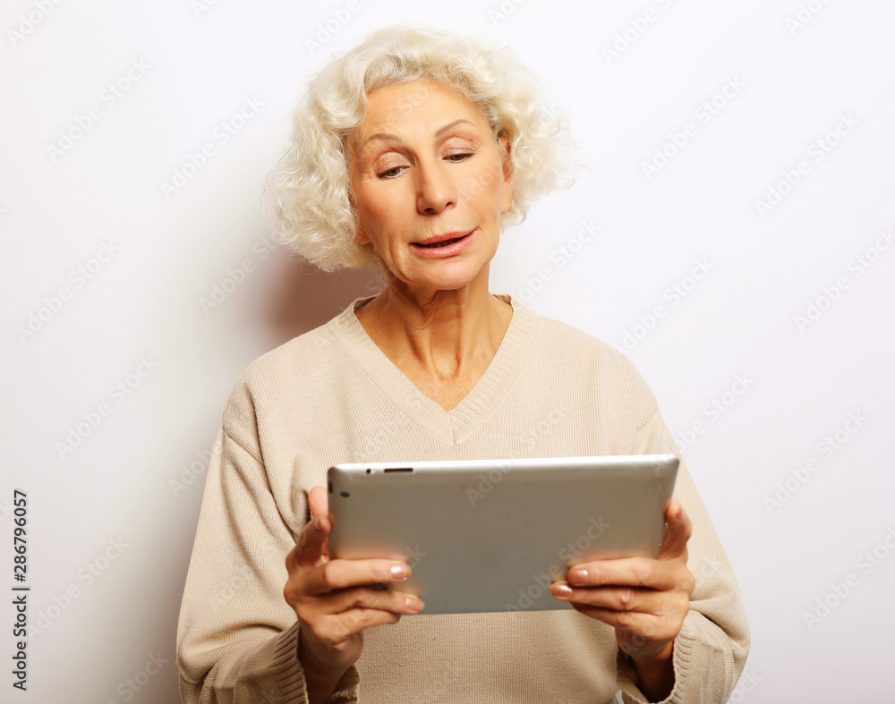 Happy mature woman using a tablet, communicates with children and grandchildren Happy mature woman using a tablet, communicates with children and grandchildren