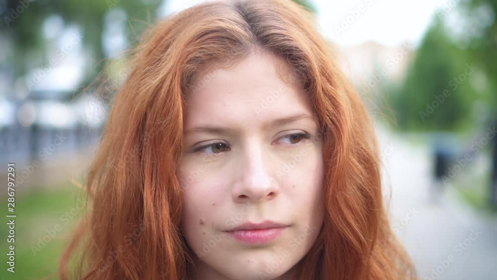 Portrait of beautiful red-haired young woman smiling happy female student looking at camera in city street background Portrait of beautiful red-haired young woman smiling happy female student looking at camera in city street background