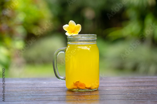 Energy tonic drink with turmeric, ginger, lemon and honey in glass mug, nature background, close up