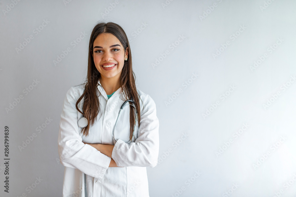 Portrait of an attractive young female caucasian doctor in white coat. Smiling female medical doctor, healthcare professional with labcoat and stethoscope. Isolated on grey background. Portrait of an attractive young female caucasian doctor in white coat. Smiling female medical doctor, healthcare professional with labcoat and stethoscope. Isolated on grey background.