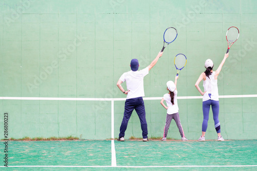 テニスの練習をする父と母と娘