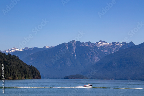A boat driving on the water with mountains in the background.