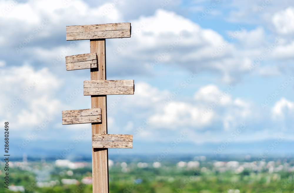 Old wooden signpost against blue sky with five sign choices pointing in different directions.