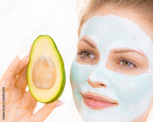 Girl facial mud mask holds avocado fruit