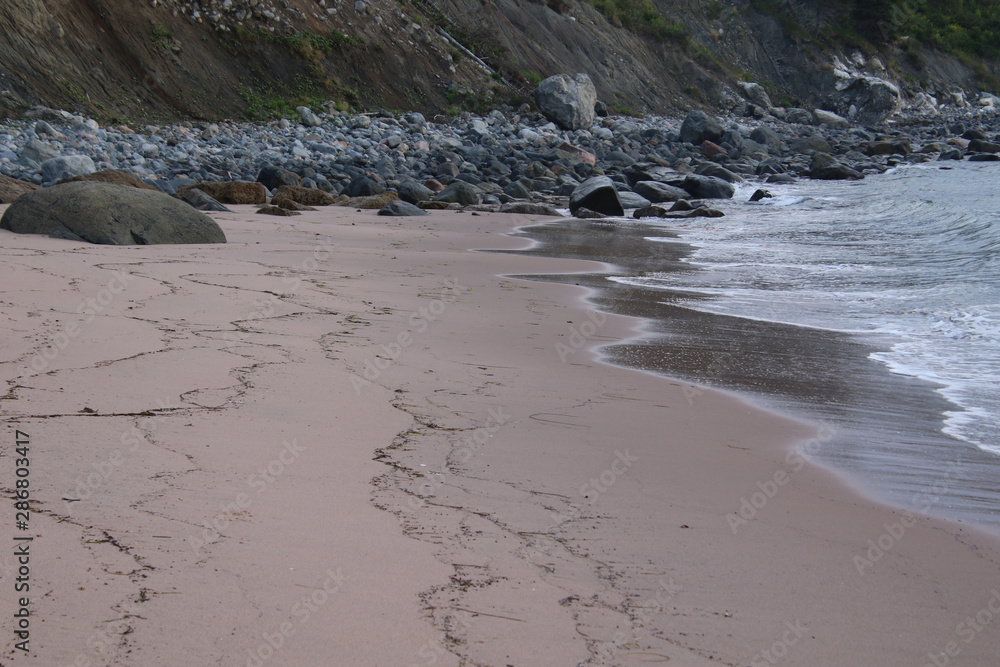Fototapeta premium A sandy beach leading to a rocky beach