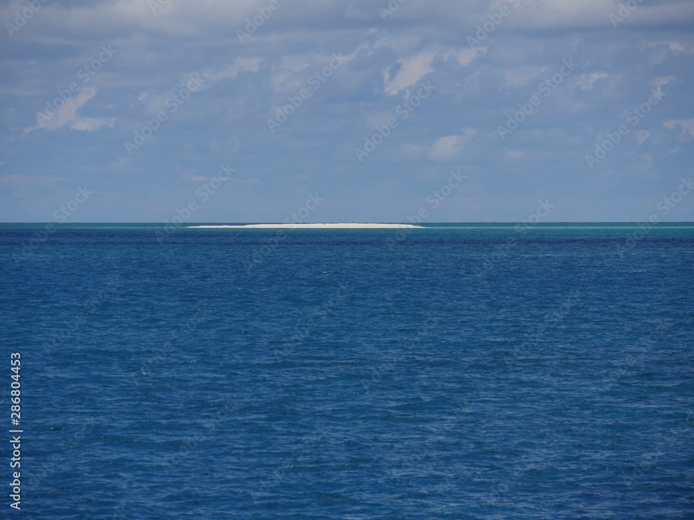 White stretch of sandbar in the middle of the ocean in the distance