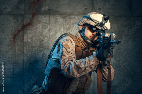 American private military contractor shooting a rifle. Studio shot
