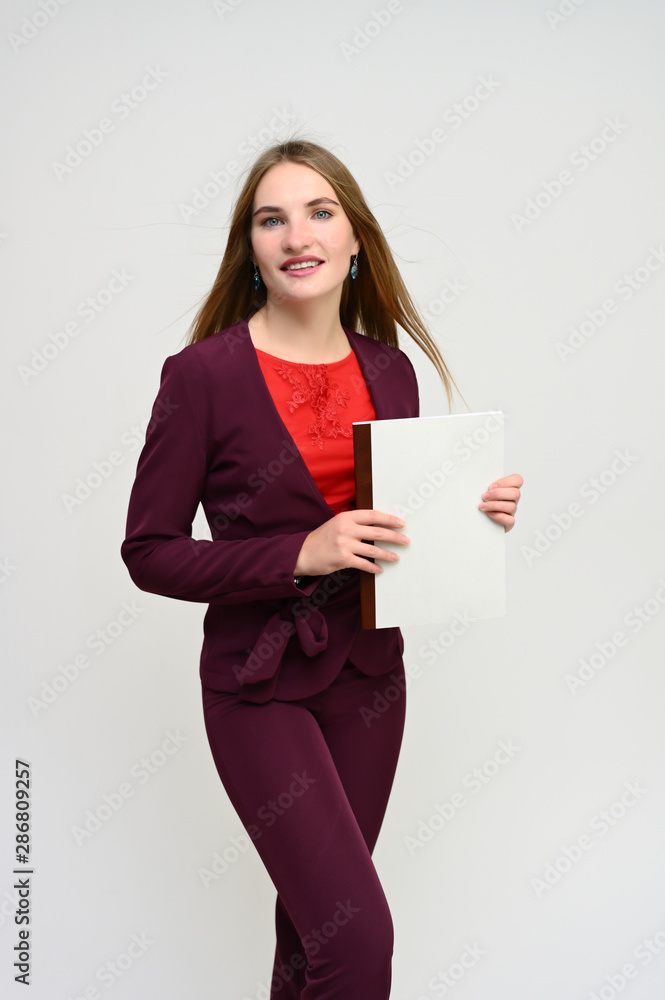 Vertical portrait of a pretty secretary manager brunette girl with long flying hair in a burgundy business suit with a folder in her hands on a white background. Smiling, showing emotions. Vertical portrait of a pretty secretary manager brunette girl with long flying hair in a burgundy business suit with a folder in her hands on a white background. Smiling, showing emotions.