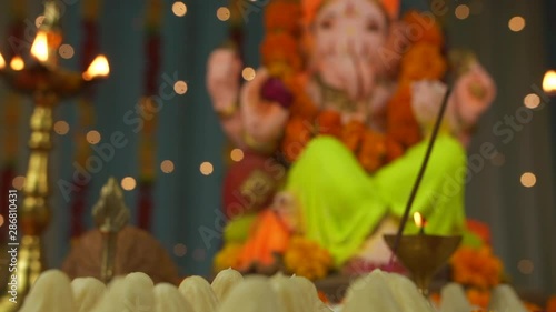 Low angle shot of Lord Ganesha idol on Ganesh Chaturthi - Indian Festival. Decorated Ganesh Ji Idol kept on a decorated platform - Indian festival for Hindus. Flowers  Lamps with Modak - Ganesh Ji ... photo