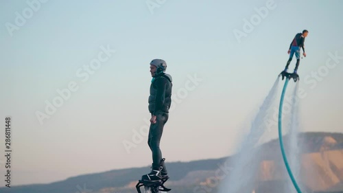 Confident man in black standing on flyboard high in air