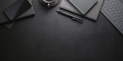 Top view of dark stylish workplace with smartphone and office supplies