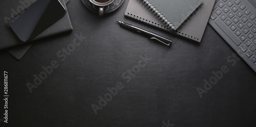 Top view of dark stylish workplace with smartphone and office supplies