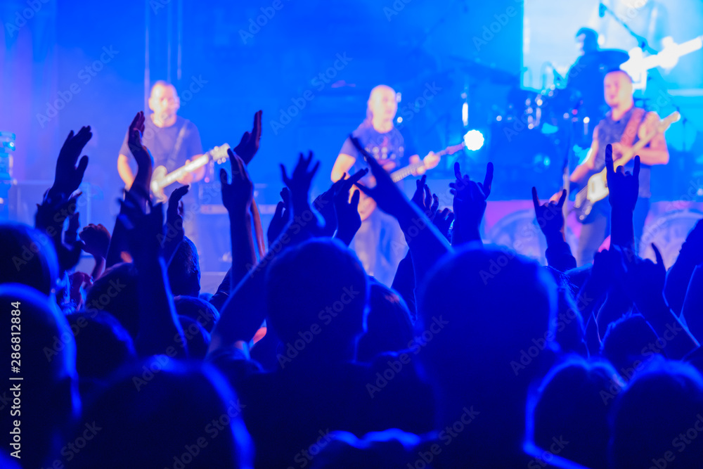 Fans cheering musicians on stage at live rock music concert