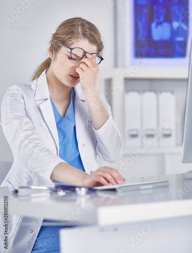 Young female doctor tired after working with computer © lenetsnikolai