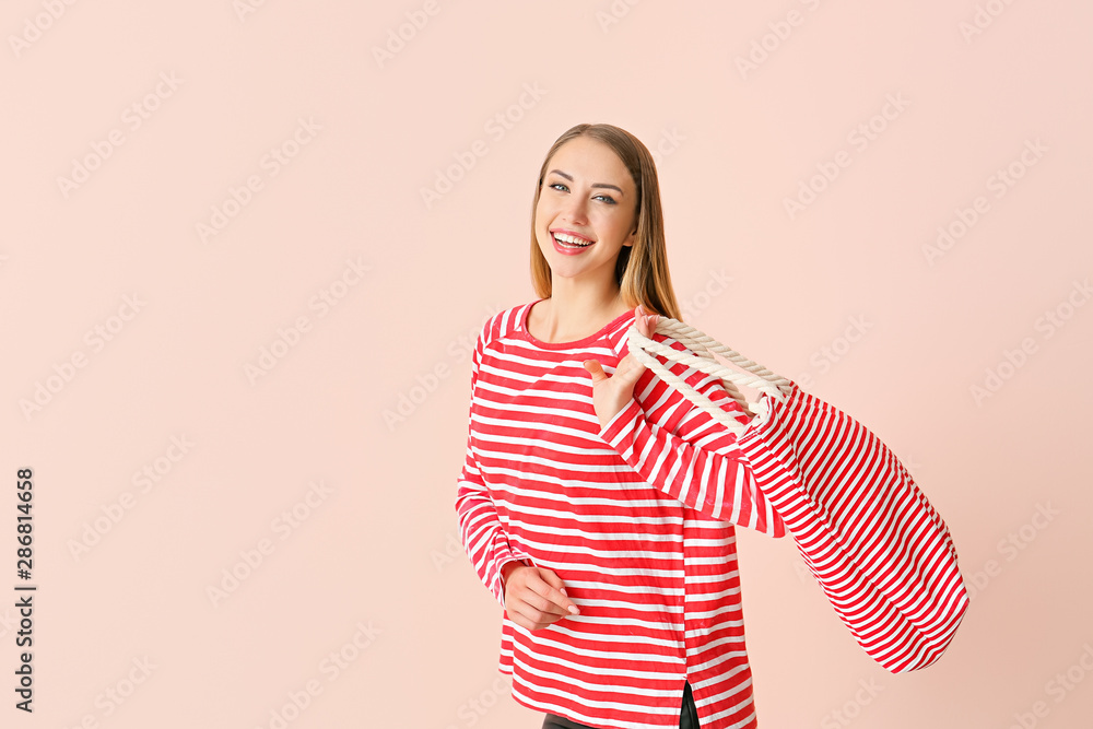 Obraz premium Beautiful young woman with bag on color background