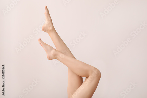 Legs of beautiful young woman on light background