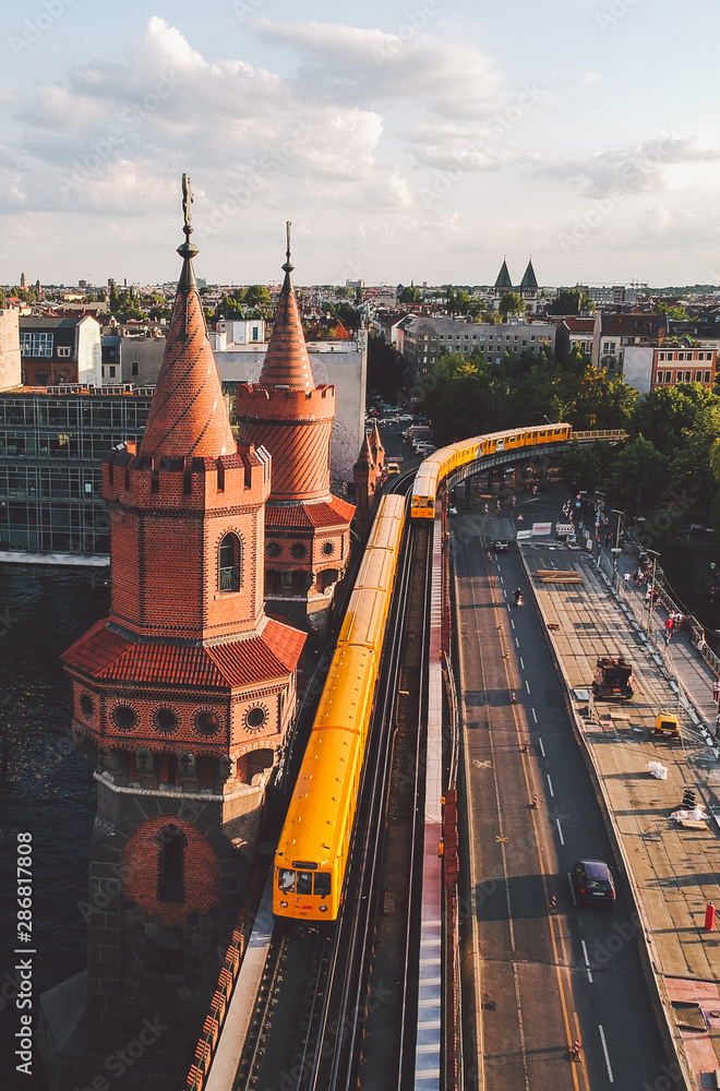 Yellow U-Bahn trains passing Oberbaumbrücke (Oberbaum bridge) in Berlin, Germany at sunset