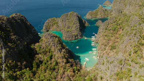 Aerial view tourist boats in lagoons. Kayangan Lake. lagoons  mountains covered with forests.coves with blue water among the rocks. Seascape  tropical landscape. Palawan  Philippines