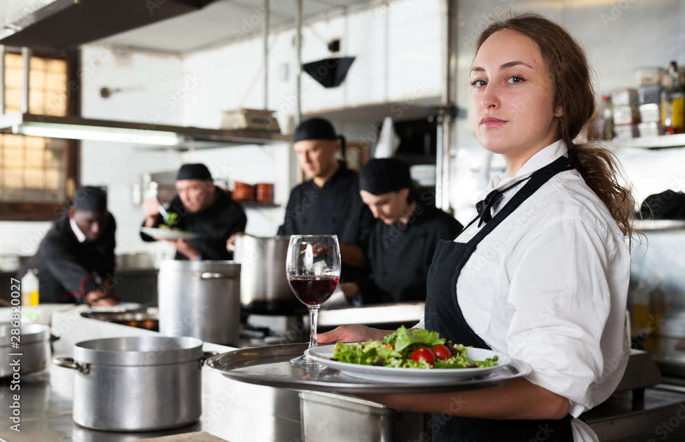Waitress holding cooked meals at kitchen restaurant