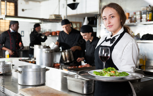 Fototapeta Naklejka Na Ścianę i Meble -  Professional waitress holding serving tray at restaurant kitchen