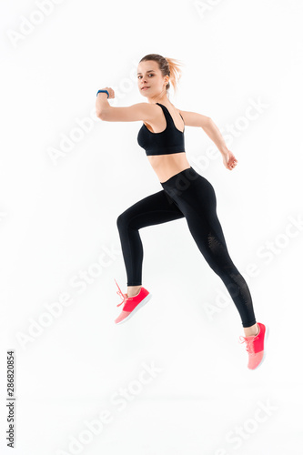 Young sporty blond woman in a black sportswear jumping isolated over white background