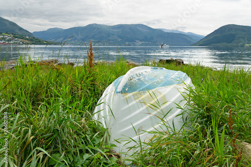 Upturned boat on green coast of village Rosendal, Norway