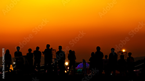 Silhouette of many tourists are taking pictures by smart phone on the top of the mountain during sunset times.